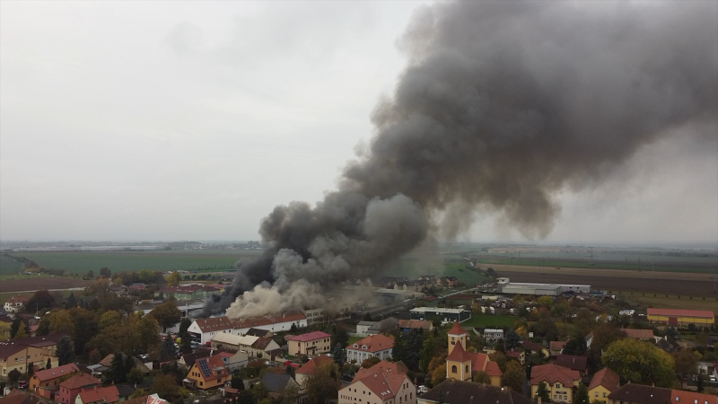 Požár haly v Nehvizdech: Hasiči vyhlásili třetí stupeň poplachu, nad město stoupá dým